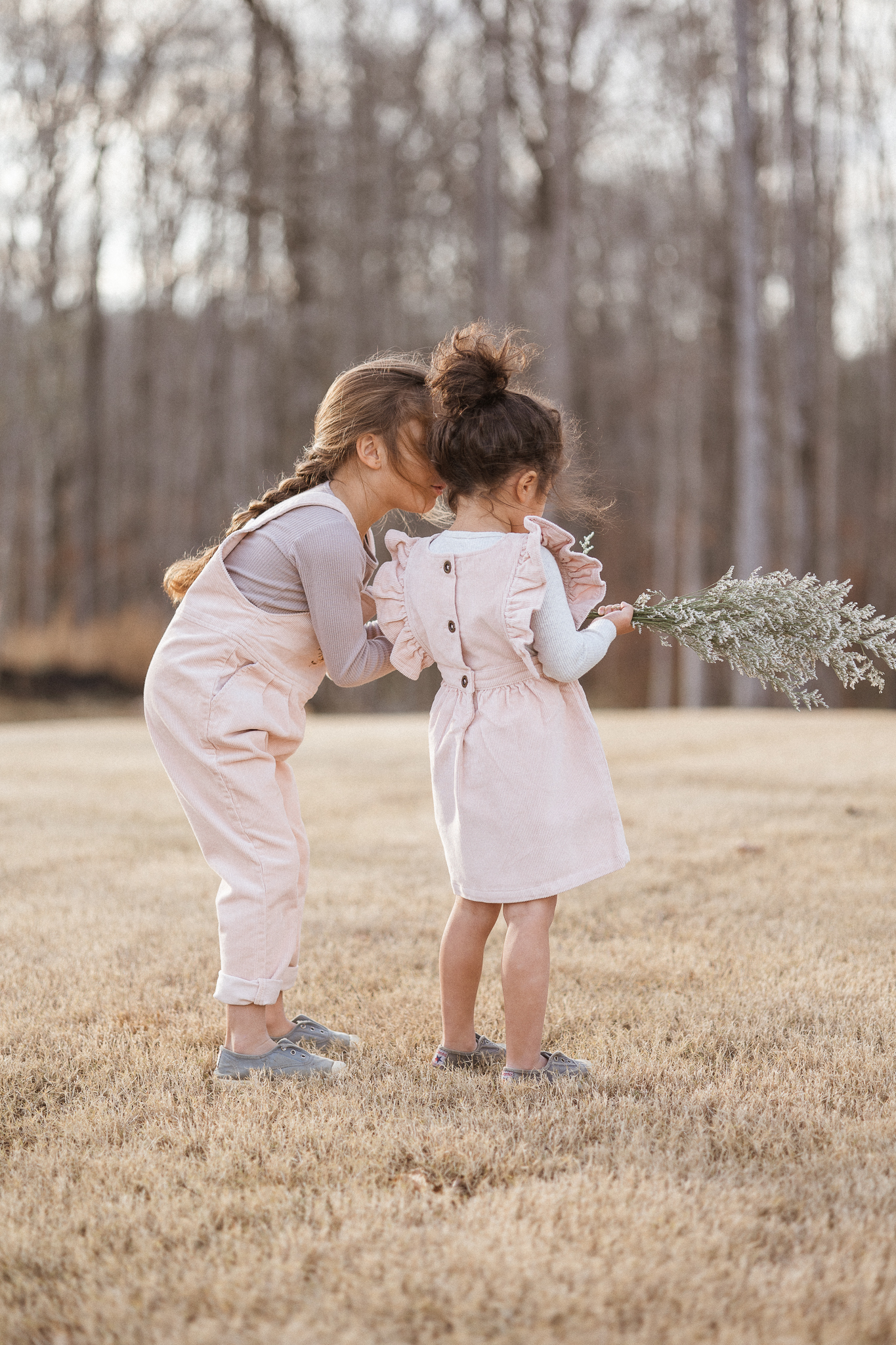 outdoor image of two girls in matching outfits holding delicate flowers motherhood photography blog